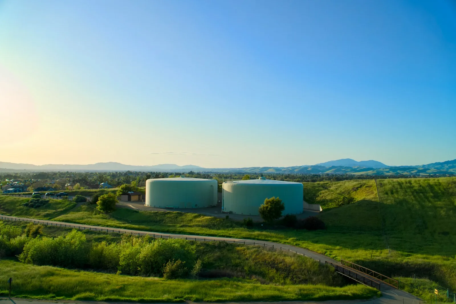 Two water tanks sit on a hill under the sky.